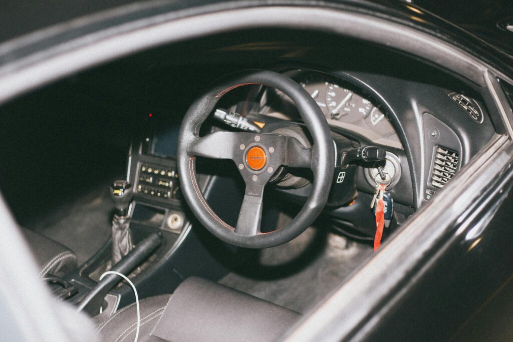 Black car interior featuring a Momo steering wheel and dashboard details.